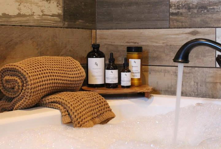 Bathroom scene with towels, bottles, and a faucet against a wooden wall.